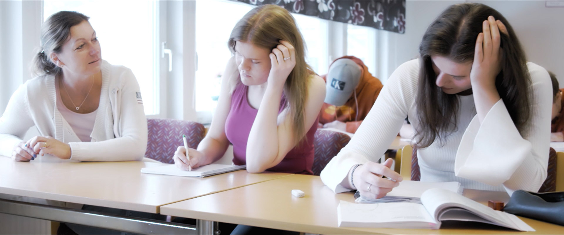 Elevassistentutbildning. Bild som visar en elevassistent som sitter brevid två deltagare.